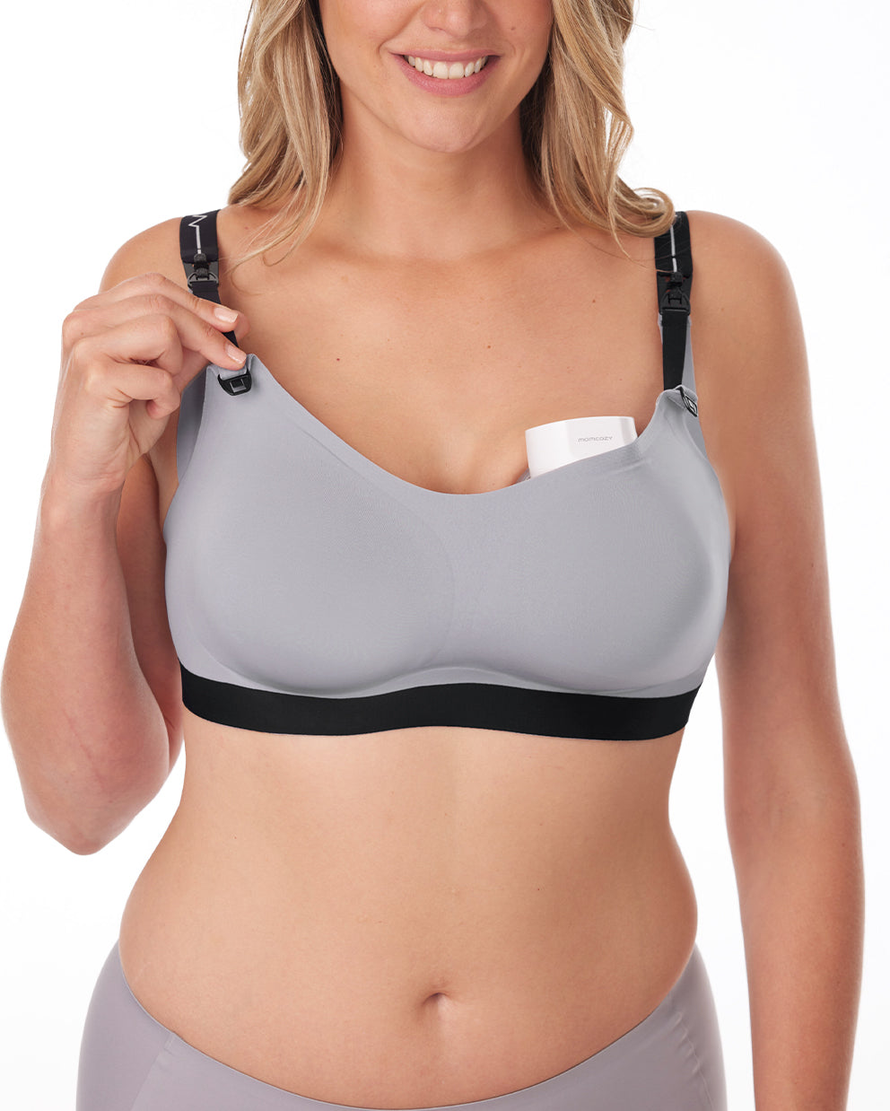 Gray nursing and pumping bra with removable straps being used by a mother for breast milk pumping.