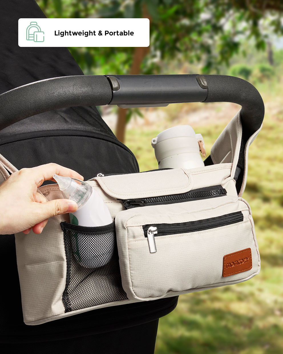 Momcozy baby nasal aspirator in stroller organizer, lightweight and portable design, beige fabric and black zippers.