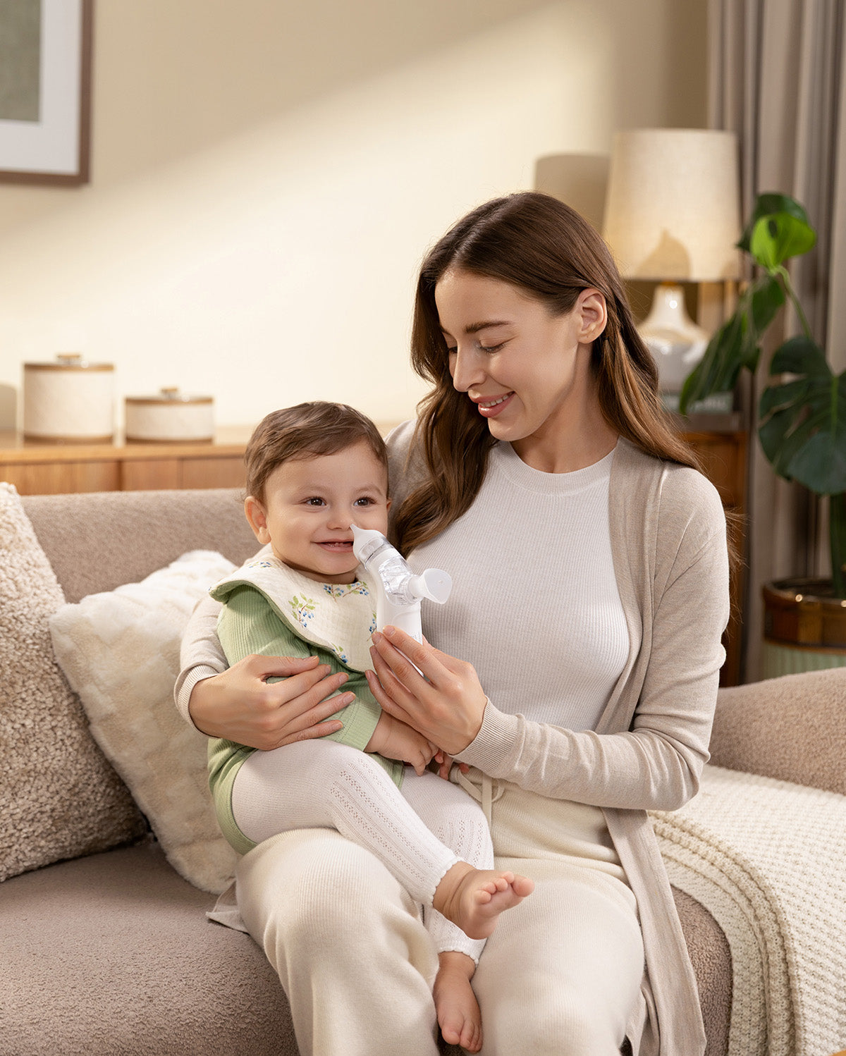 Momcozy BreezyClear™ Nasal Aspirator in use, mother holding baby, gentle suction care for babies.